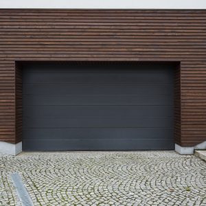 Big garage with black door and wooden wall in spachpuseious yard